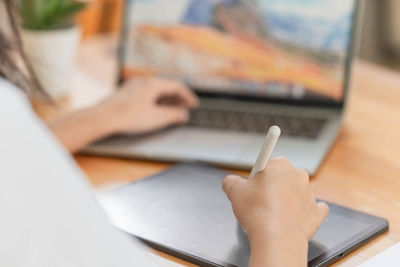 Lifestyle and technology concept, young asian woman writing on tablet and using laptop to working