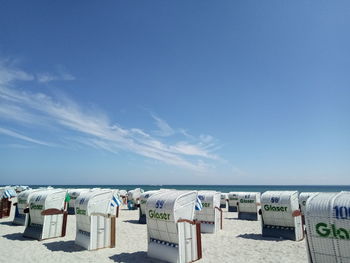 Hooded chairs on beach against blue sky