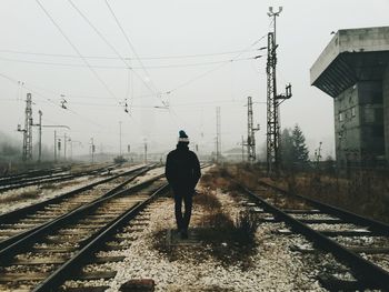 Rear view of man walking on railway tracks