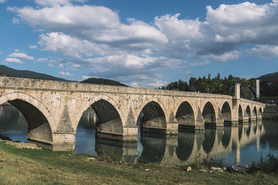 Arch bridge over river against sky