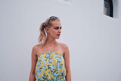 Young woman standing against white wall