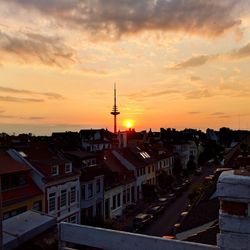 Communications tower in city at sunset