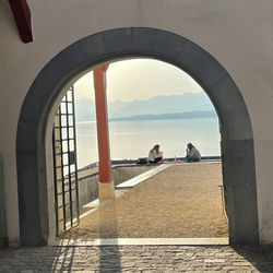 People looking at sea seen through arch