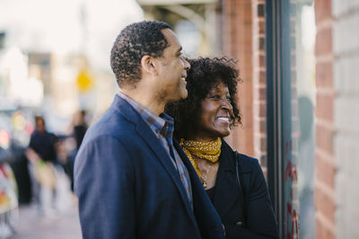 Smiling couple doing window shopping in city