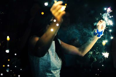 Woman holding sparklers at night