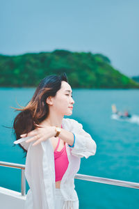 Portrait of young woman standing against sea