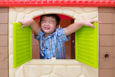 Happy boy playing in toy house