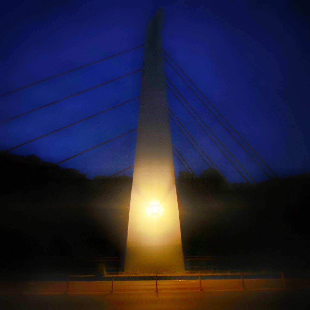 LOW ANGLE VIEW OF ILLUMINATED BRIDGE AT SUNSET