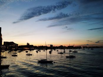 Boats moored at harbor against sky during sunset