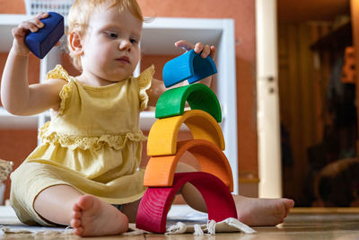 Cute girl playing with multi colored toy at home