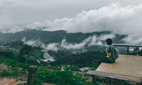 Rear view of man looking at mountains against sky