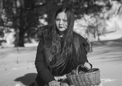 Young woman sitting in basket during winter