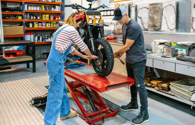 Mechanic team adjusting motorbike wheel on factory