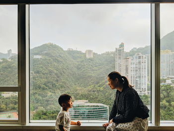 Rear view of two women looking through window