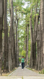 Woman on road amidst trees in forest