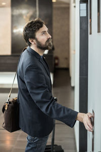 Businessman pushing button of elevator at hotel