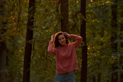 Rear view of woman standing against trees in forest