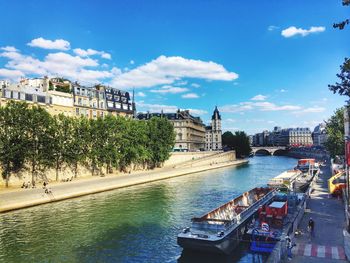 View of city at waterfront against cloudy sky