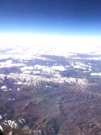 Aerial view of snowcapped mountains against blue sky