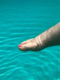 Low section of man relaxing in swimming pool