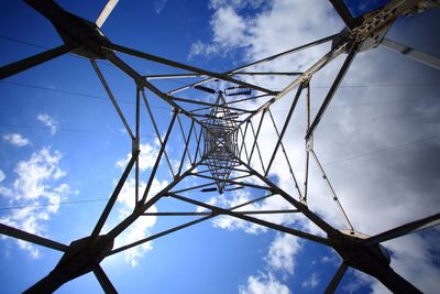 Low angle view of electricity pylon against blue sky