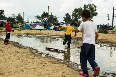 Boys playing in puddle at refugee camp