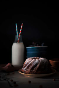 Close-up of sweet food in plate with milk bottle on table