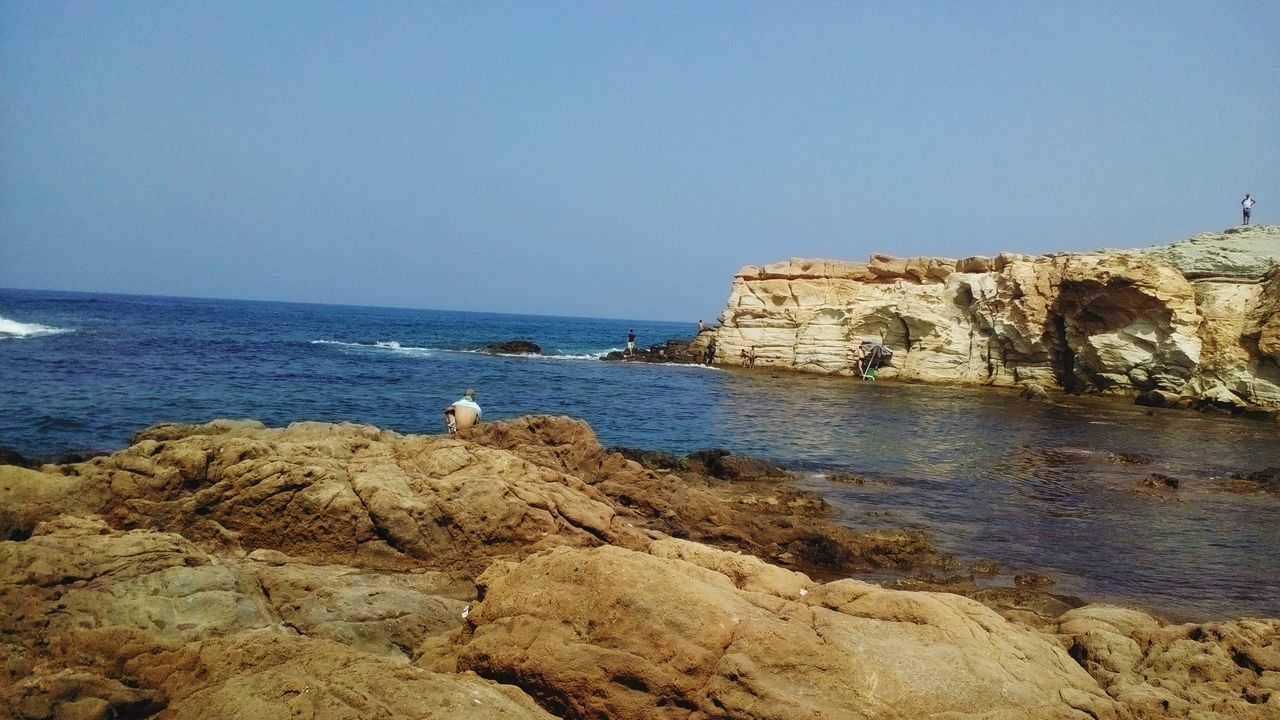 clear sky, sea, copy space, water, horizon over water, blue, rock - object, built structure, tranquility, architecture, beach, scenics, nature, tranquil scene, rock formation, beauty in nature, shore, building exterior, rock, day