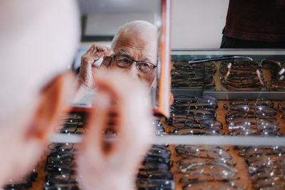 Senior man choosing eyeglasses at store