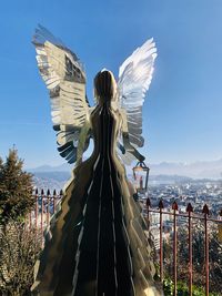 Rear view of woman statue against sky