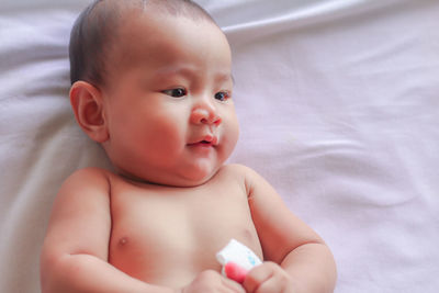 Portrait of cute baby girl lying on bed