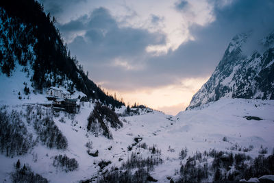 Scenic view of snow covered mountains against sky at sunset