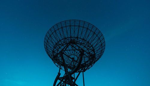 Low angle view of communications tower against blue night sky