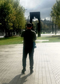 Rear view of man standing on sidewalk in city