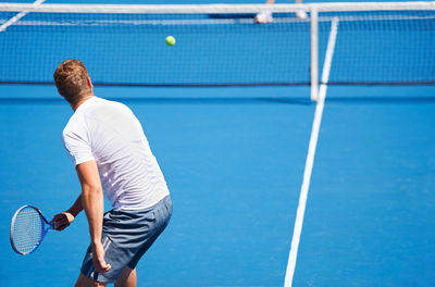 Rear view of man playing tennis