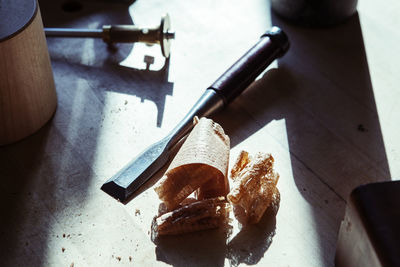 High angle view of chisel by sawdust on wooden table in workshop