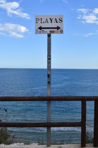 Information sign by sea against sky