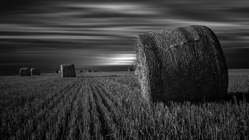 Hay bales on field against sky