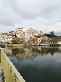 Buildings by river against sky in city