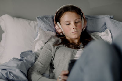 Teenage girl lying on bed watching movie through digital tablet at home