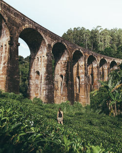 Rear view of woman standing against viaduct