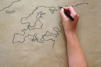 Close-up of hand drawing world map on paper