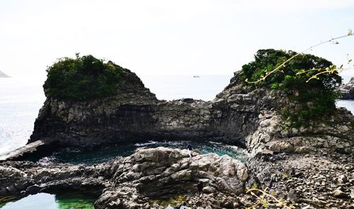 Rock formation by sea against sky