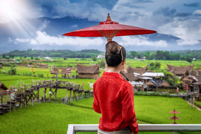 Rear view of woman holing umbrella standing against sky