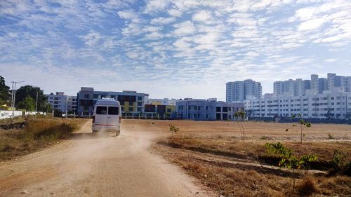 Road leading towards city against sky