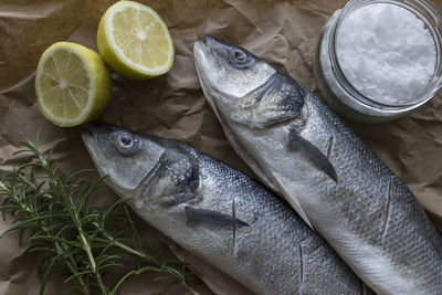 High angle view of fish with ingredients on brown paper