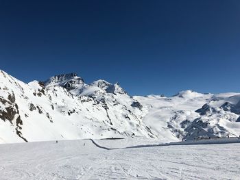 Scenic view of snowcapped mountains against clear blue sky