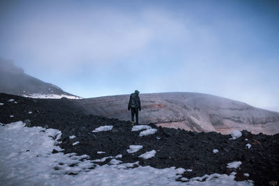 Rear view of male hiker hiking on mountain during winter