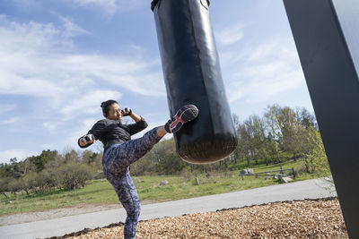 Woman training with boxing bag in outdoor gym