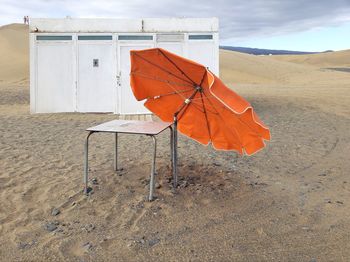 Orange umbrella on beach against sky